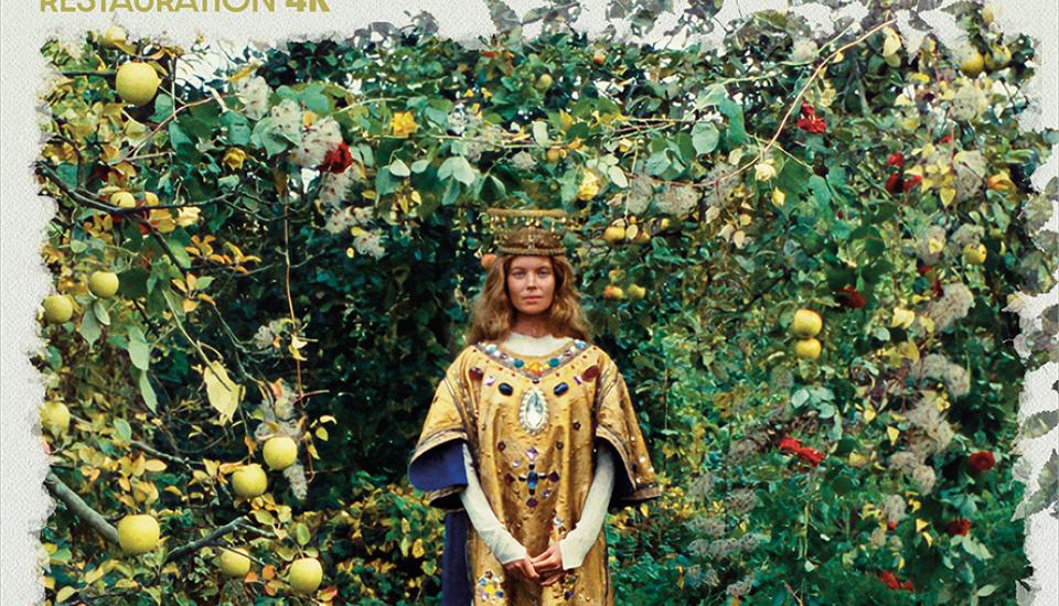 Un personnage féminin, richement vêtu de vêtement religieux, dans un décor naturel fait de verdure. Au premier plan, des pommes au sol.
